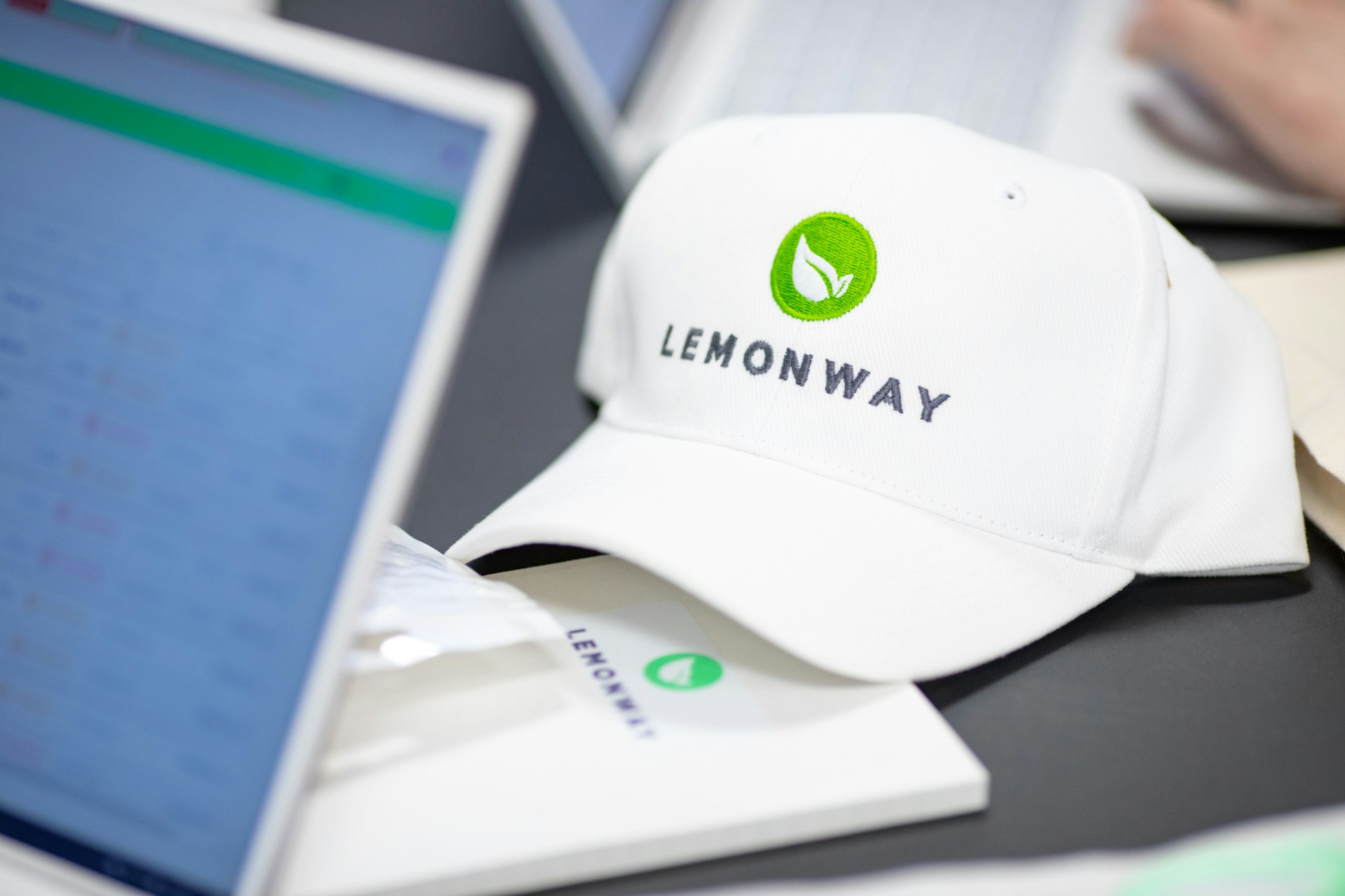 Goodies Lemonway sur un bureau : casquette et carnet avec logo Lemonway + un ordinateur