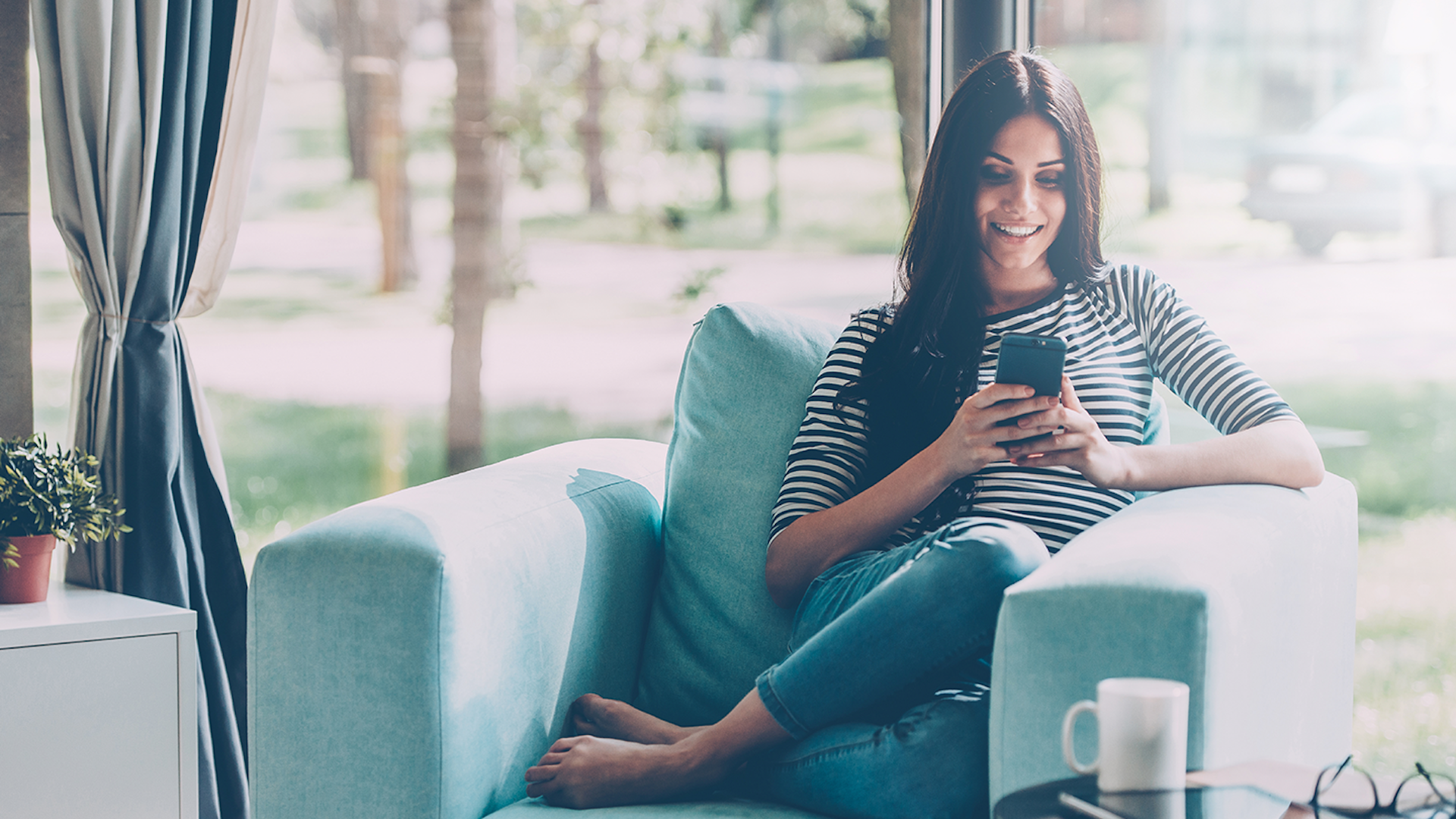 photo of a woman sitting on her couch scrolling trough her phone