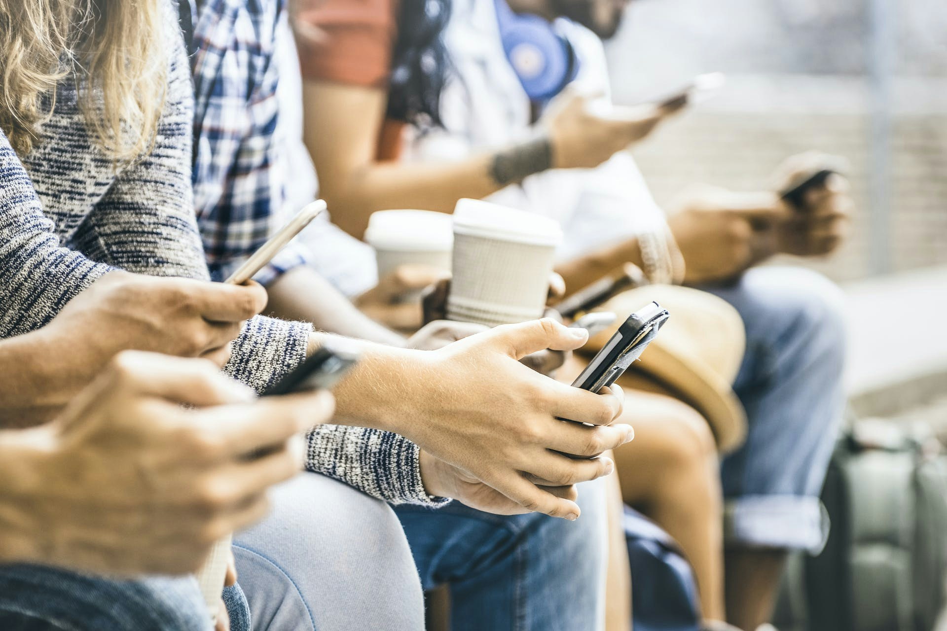 Foto von Jugendlichen, die nebeneinander sitzen und auf ihren Smartphones scrollen