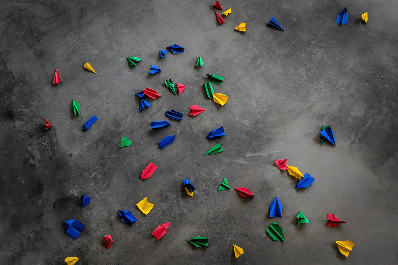 Foto grauer Hintergrund mit bunten Papierfliegern in Google Farben