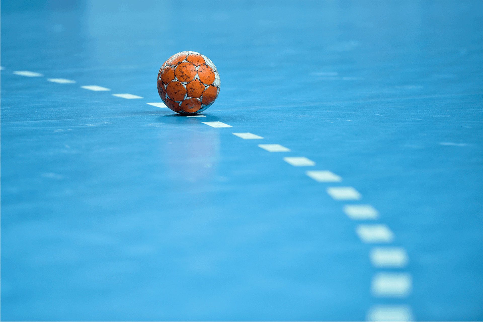Foto Handball liegt auf blauem Handballfeld