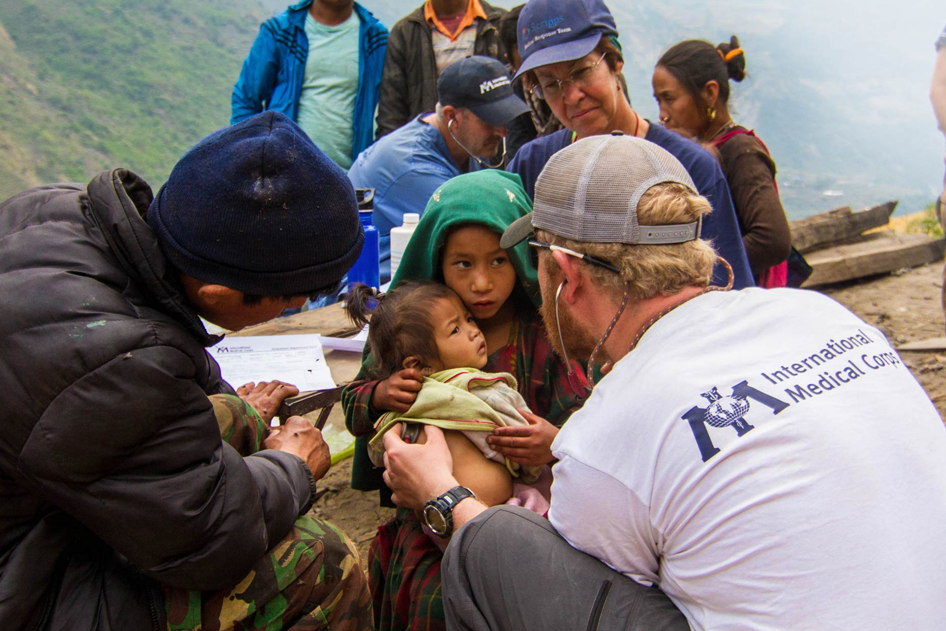 Photo of a doctor with an International Medical Corps Tshirt examining a child