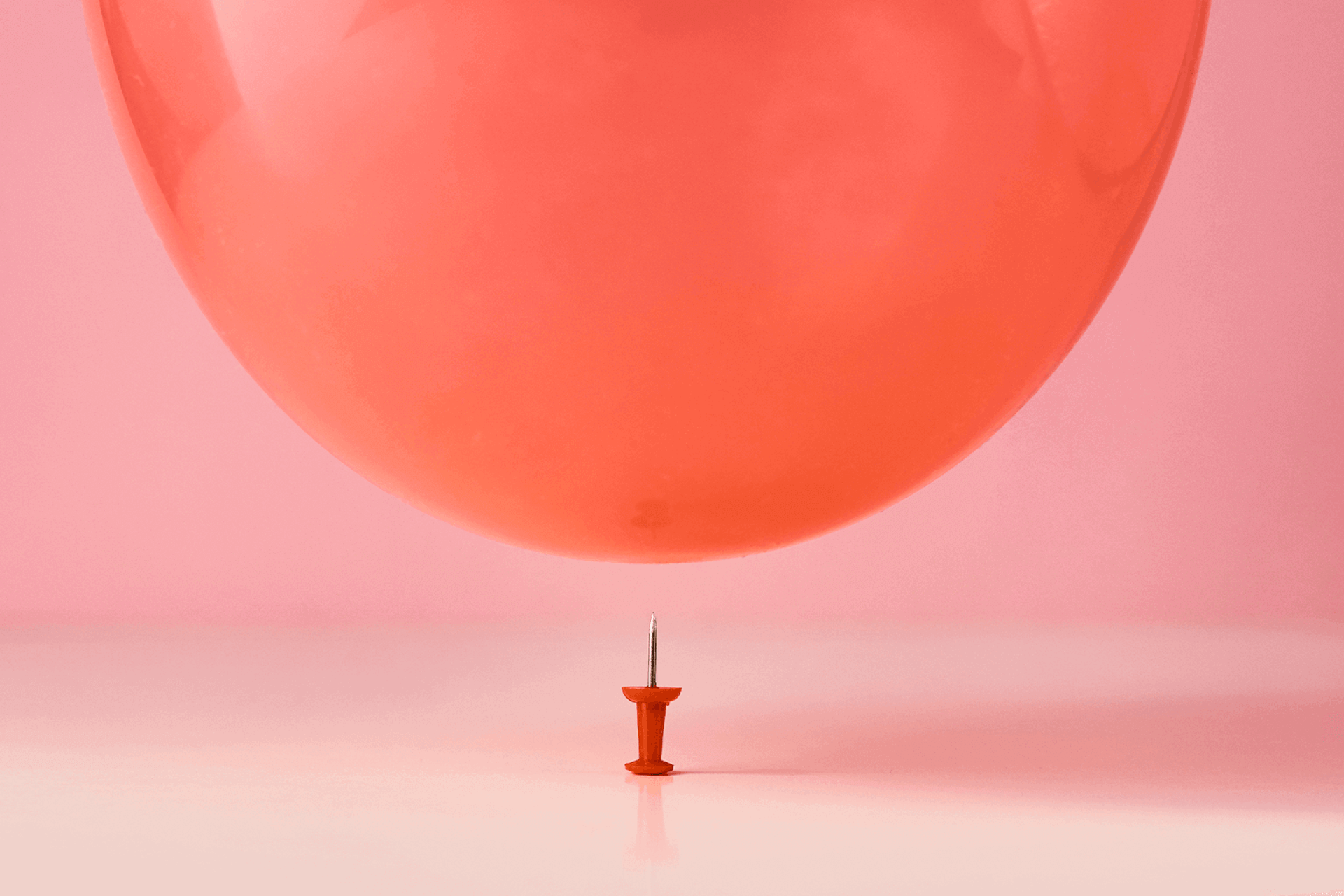 Image of a balloon almost getting popped by a needle