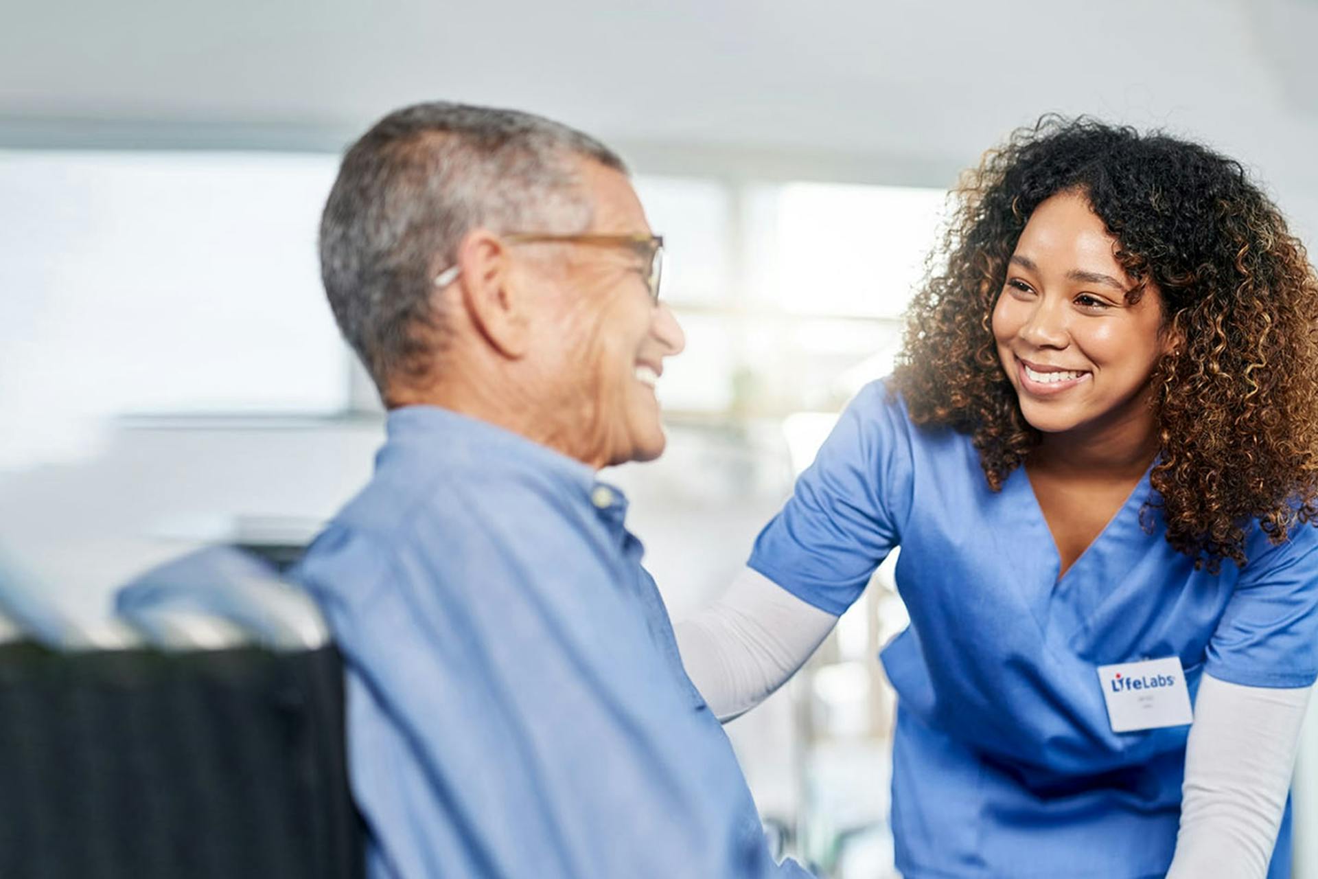 A LifeLabs technician smiles at a seated customer in this header image for a Meltwater customer story.