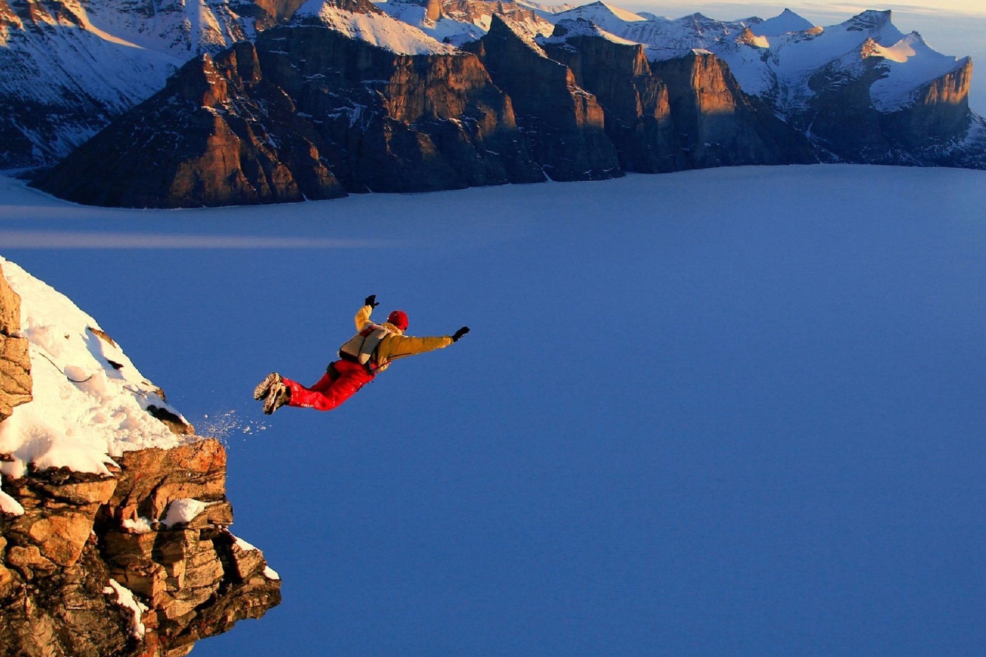 Photo of someone jumping from a snowy mountain