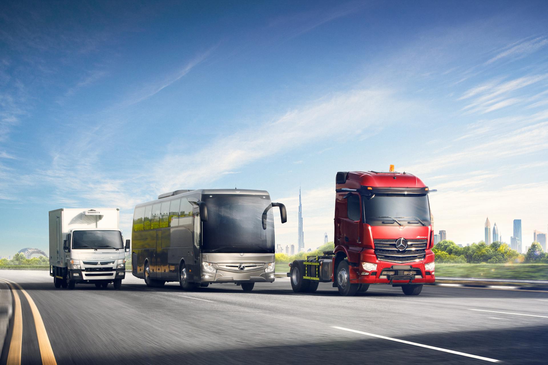 Image d'un camion rouge, d'un bus gris et d'un camion blanc sur une autoroute.