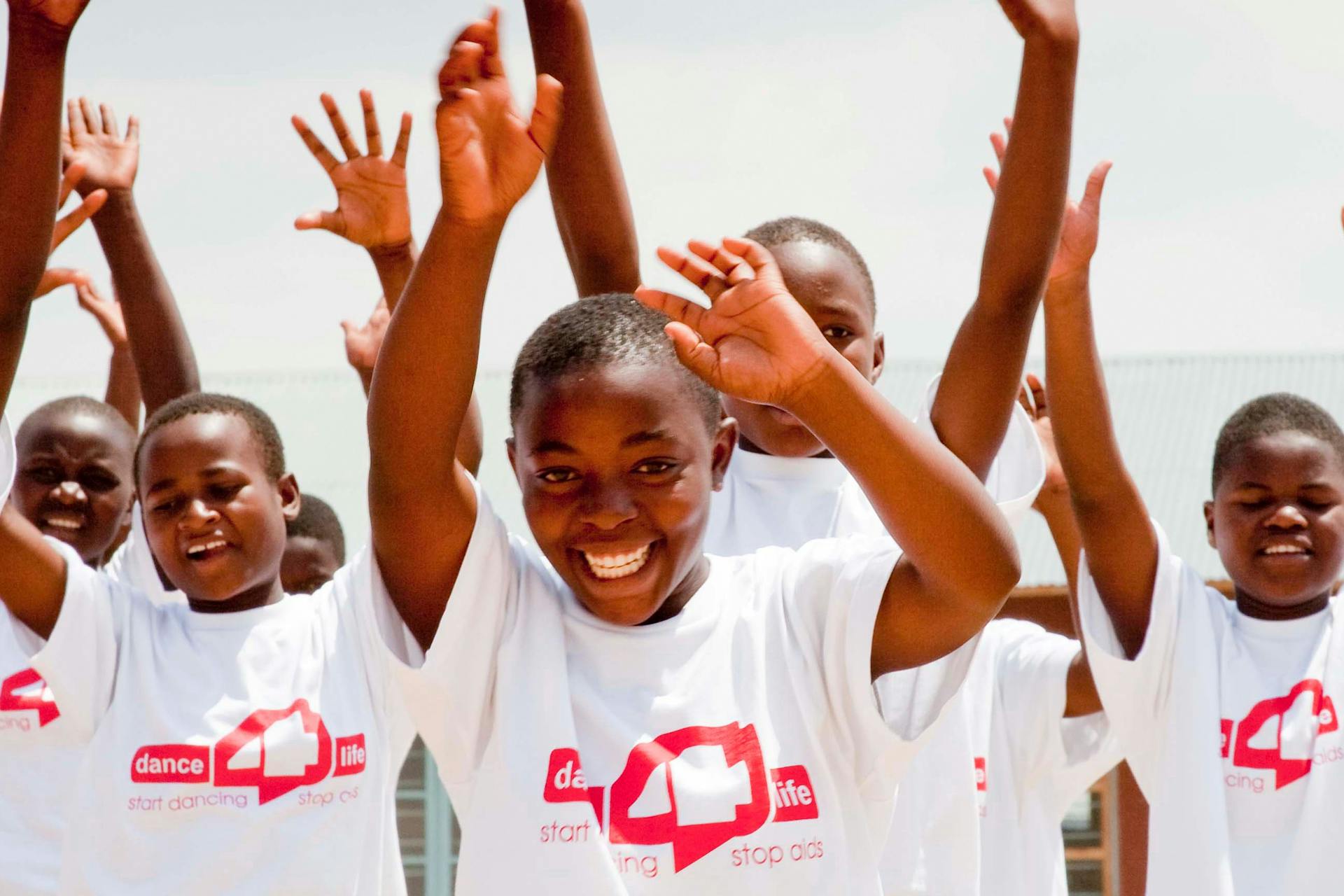 Children smiling and dancing wearing Dance4Life t-shirts