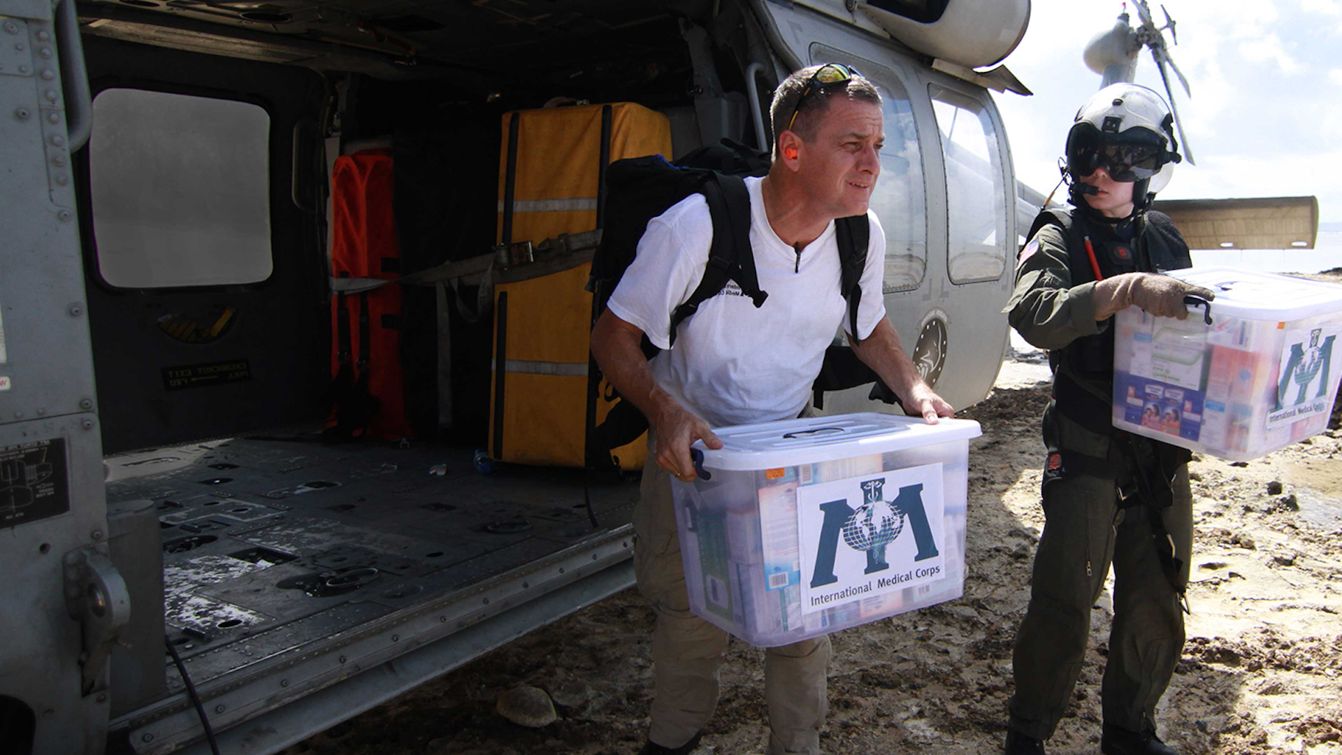 Photo of two men from International Medical Corps delivering boxes from a helicopter