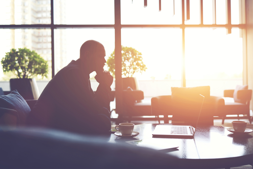 Silhouette of a man looking at a laptop screen