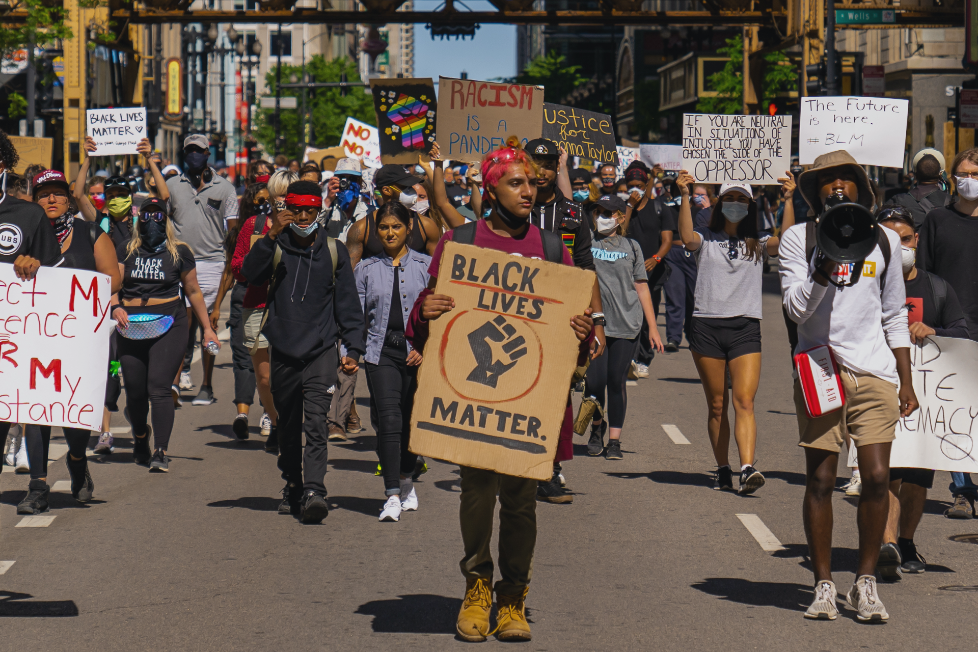 People walking in the street protesting, holding black lives matter signs 