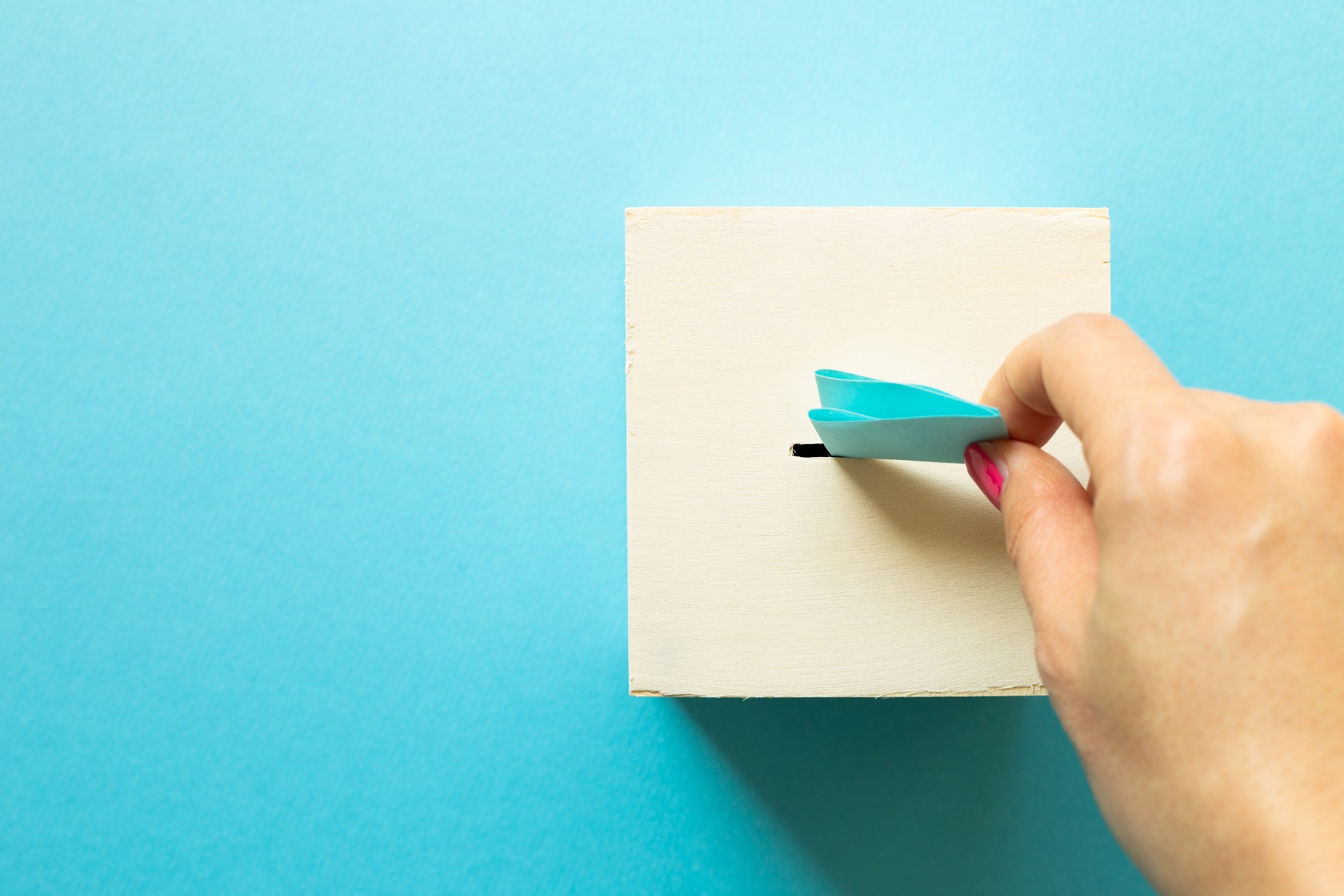 Image of hand placing a ballot into box on blue background
