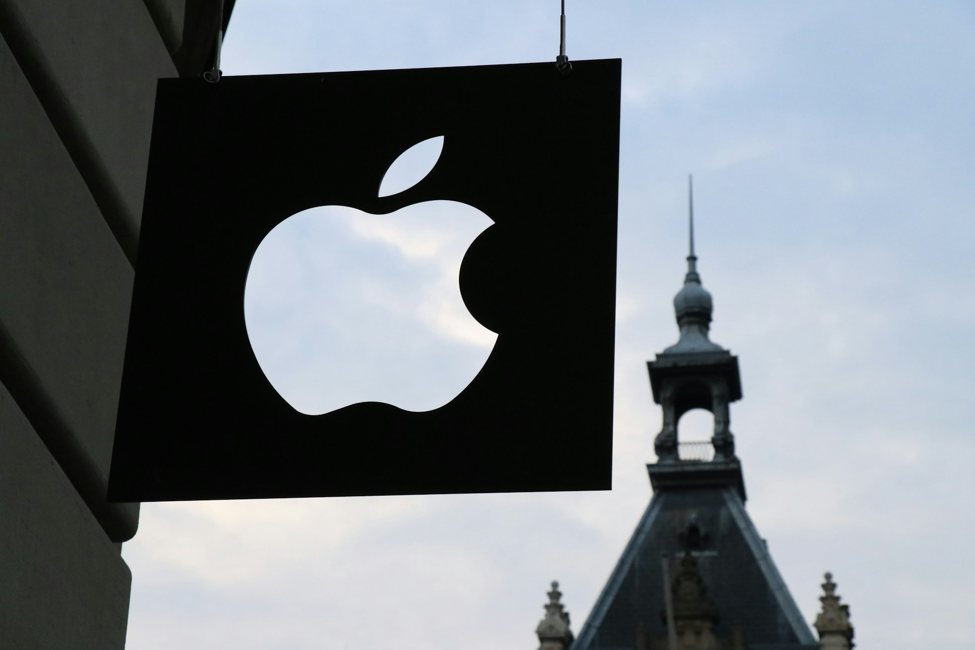 Man sieht ein Foto eines iStore Schildes, in dem das Apple Logo ausgeschnitten wurde und man durch die Transparenz den Himmel sehen kann.