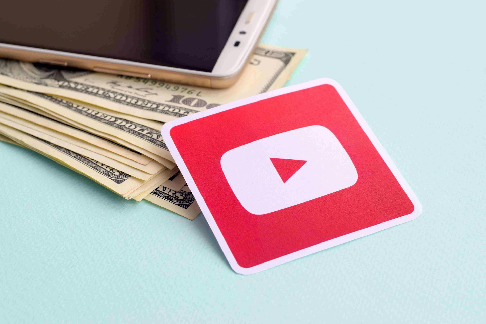 YouTubeロゴのラベル、ドル札、スマートフォン