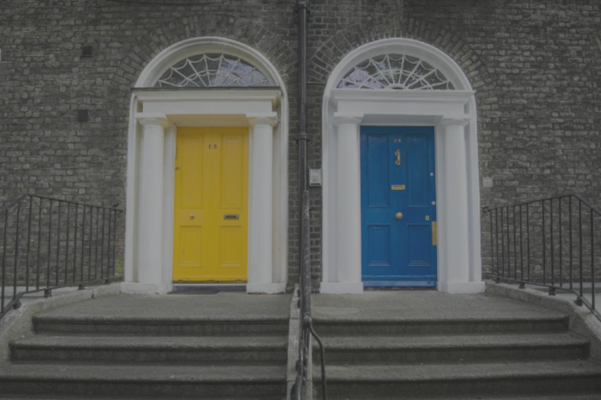 Two doors with grey steps leading up to them. One door is yellow, the other is blue.