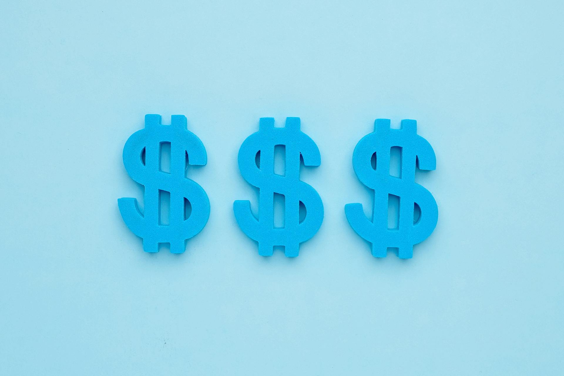 蓝色背景下的三个蓝色美元标志。美元符号代表你的营销团队可以通过Facebook领先广告产生的收入。