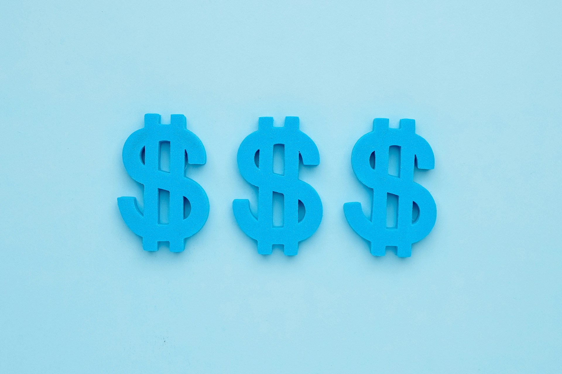 Trois signes de dollar américain bleu sur fond bleu. Les signes dollar représentent les revenus que votre équipe marketing pourrait générer via les publicités Facebook.