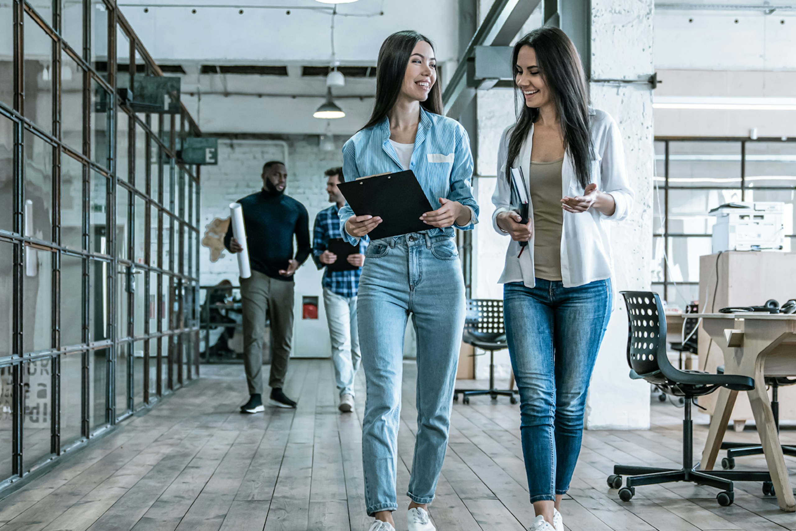 Photo of two women walking and talking in an office. Main image for a report on Marketing Reinvented.