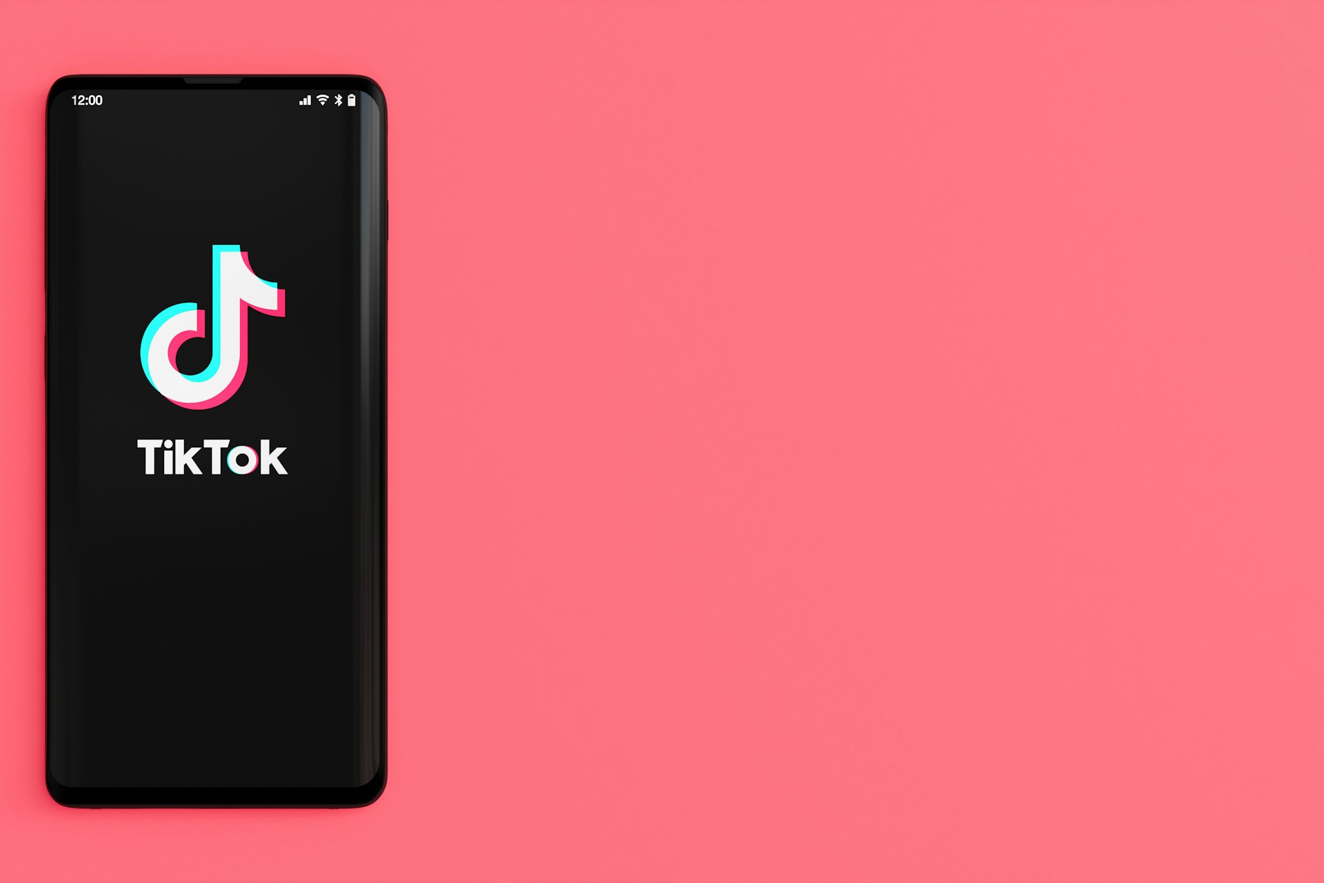 ピンクの背景にTIkTokロゴが表示されているスマートフォンが配置されている画像
