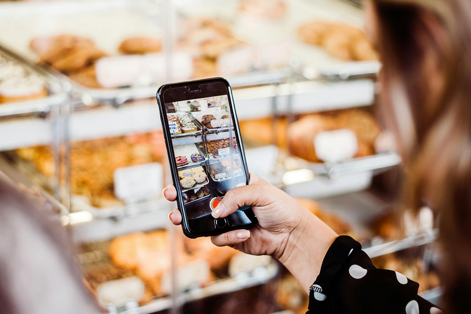 person holding a phone and taking a photograph of baked treats