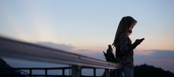 Photo of a woman with her smartphone outside in the sunset