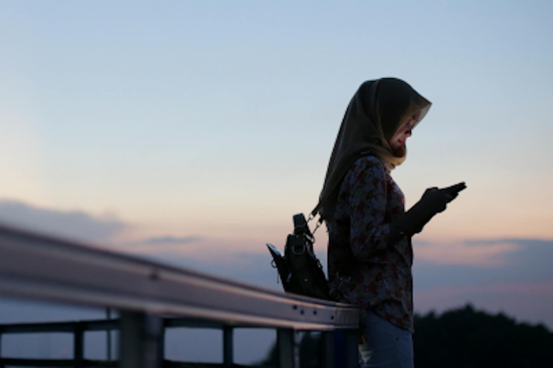 Photo of a woman with her smartphone outside in the sunset