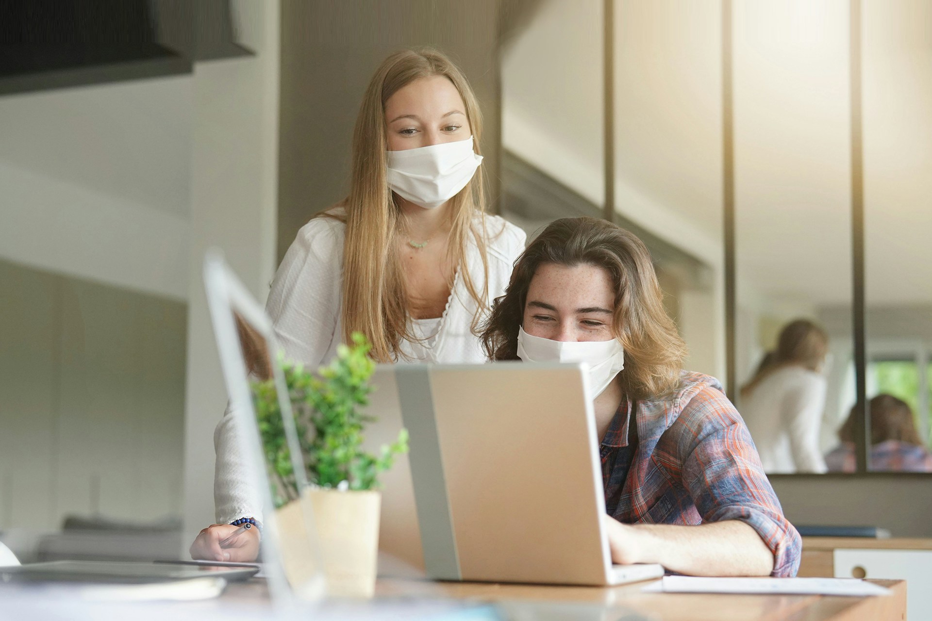 Two people in face masks looking at a laptop screen