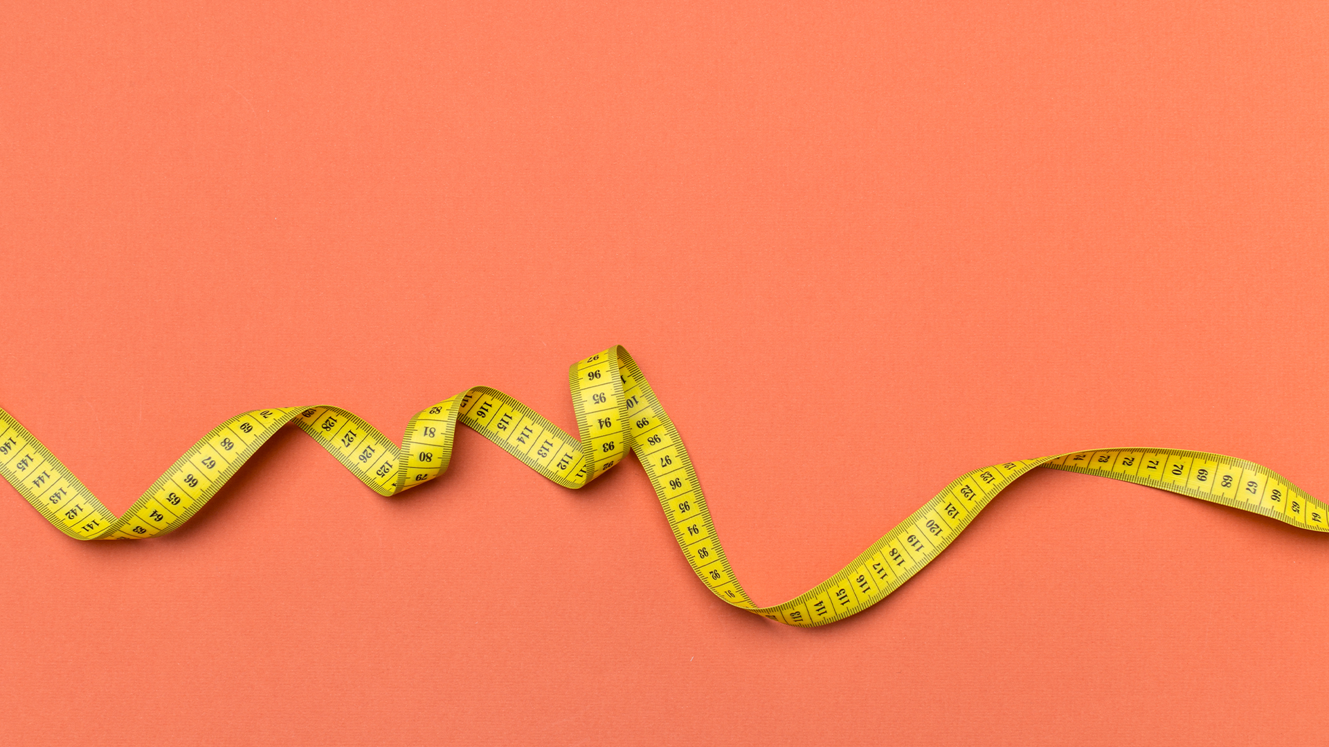 yellow tape measure against a coral pink background