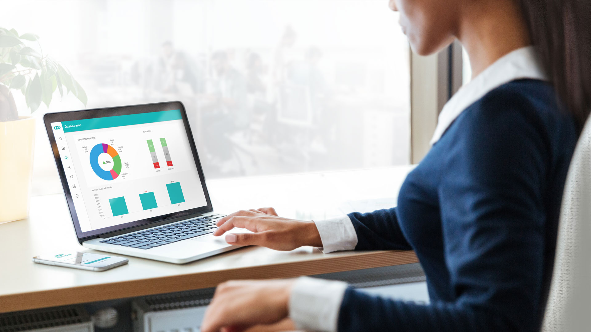 A woman at her desk viewing a Meltwater dashboard on her laptop