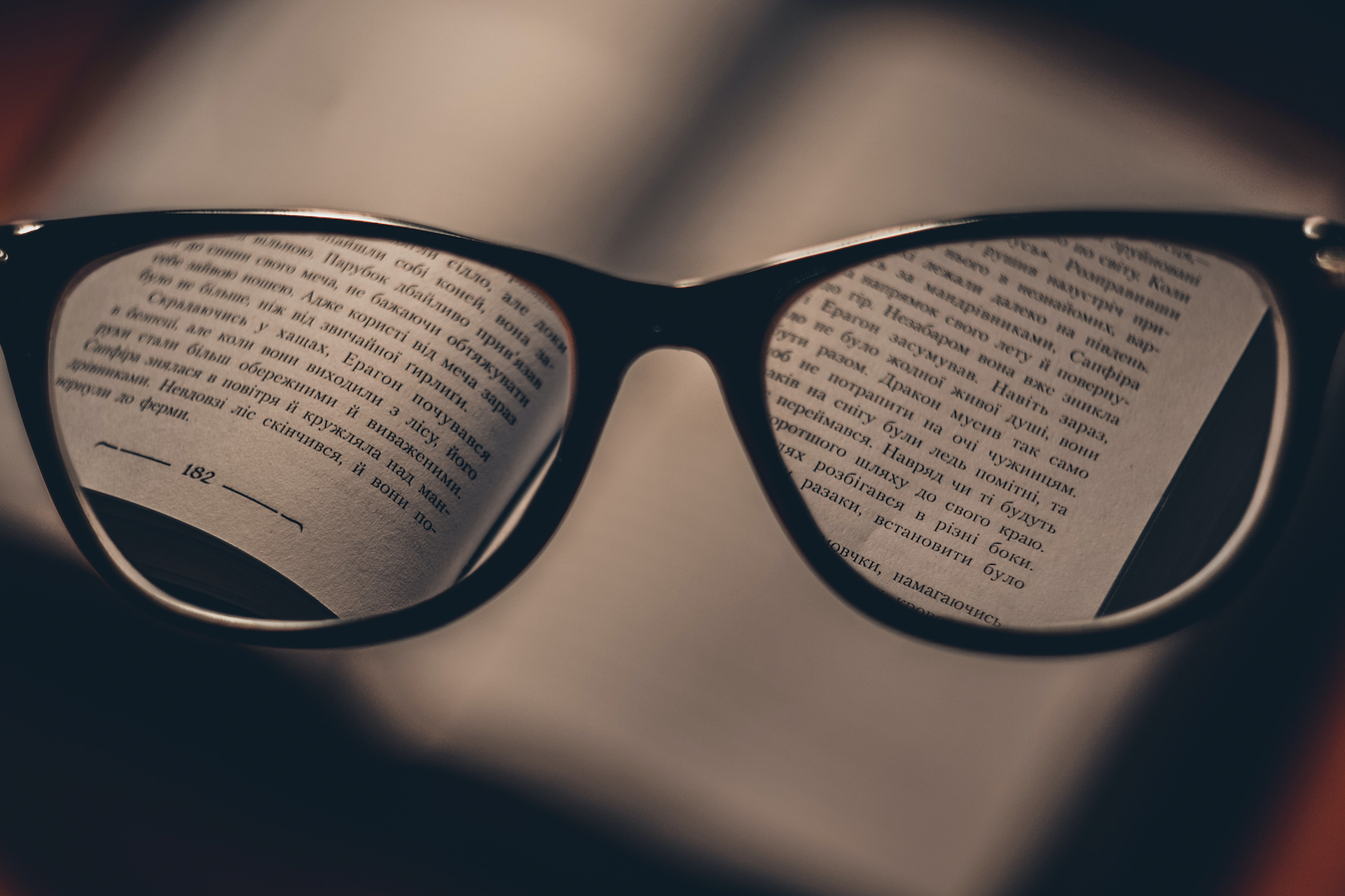 photo of a glasses held in front of an open book