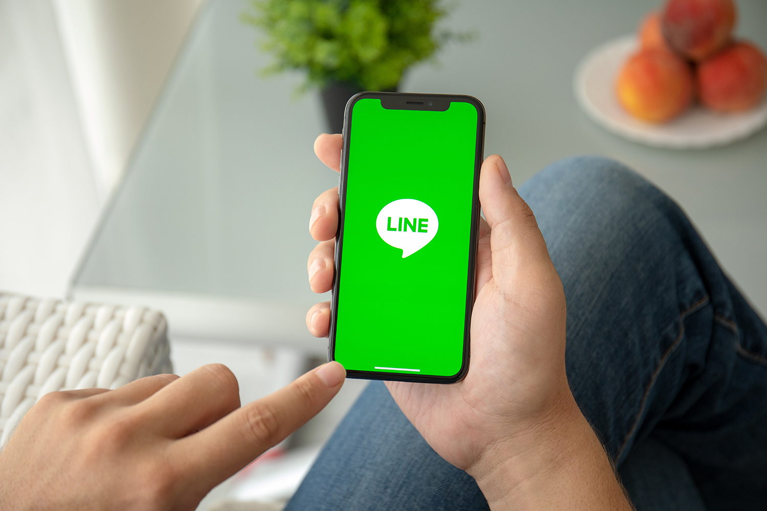 LINEロゴの表示されているスマートフォンを持っている手元の画像
