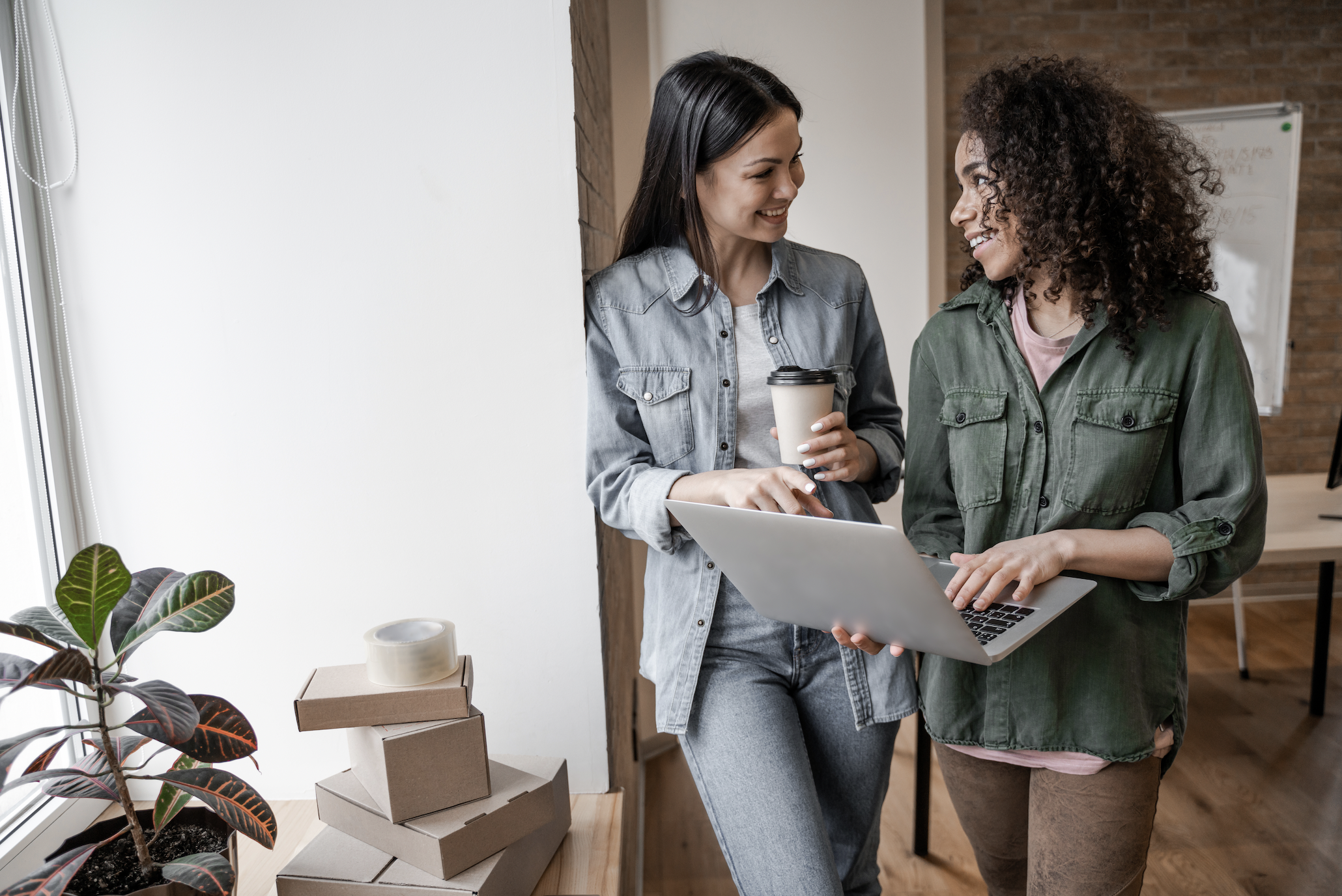 Deux femmes qui tiennent un ordinateur et un café en discutant de marketing B2B