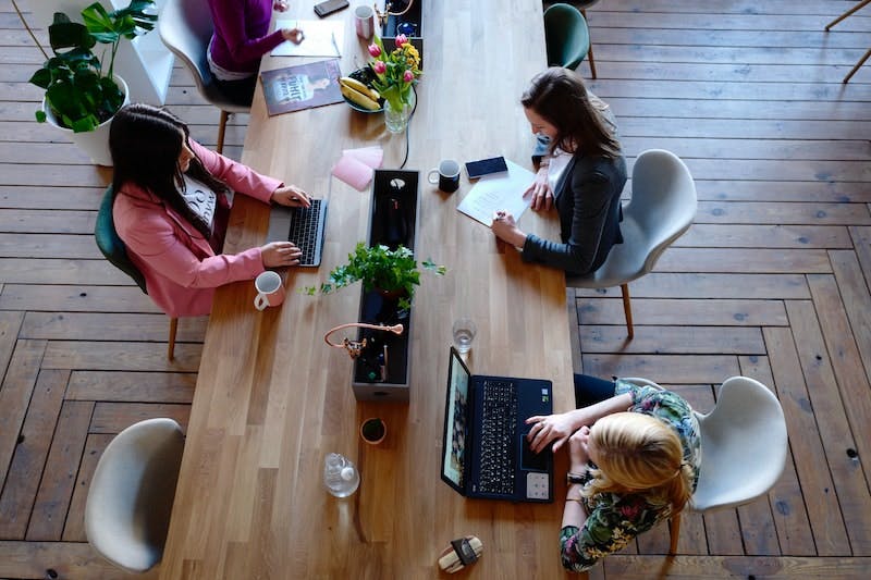 Drei Frauen sitzen in einem modernen Büro und arbeiten