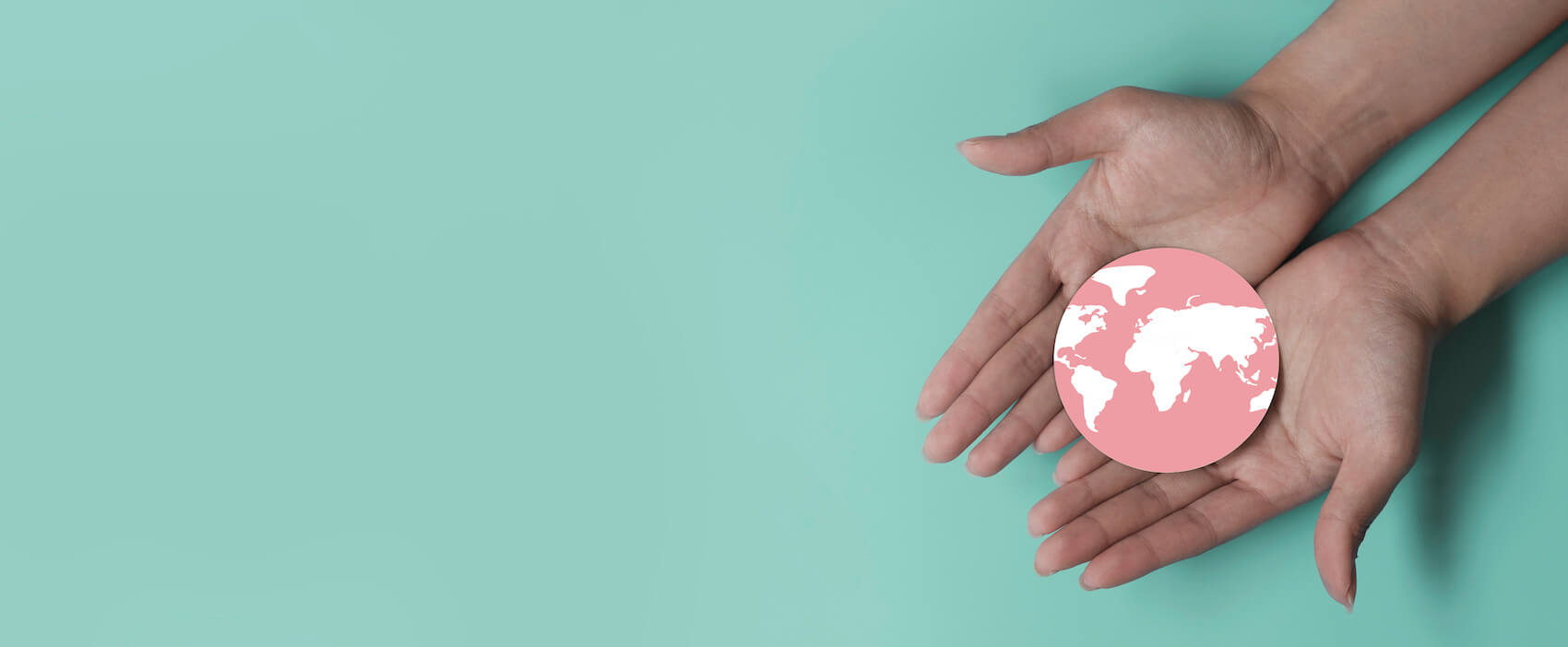 Foto von zwei Händen, die eine Welt halten vor einem türkisen Hintergrund