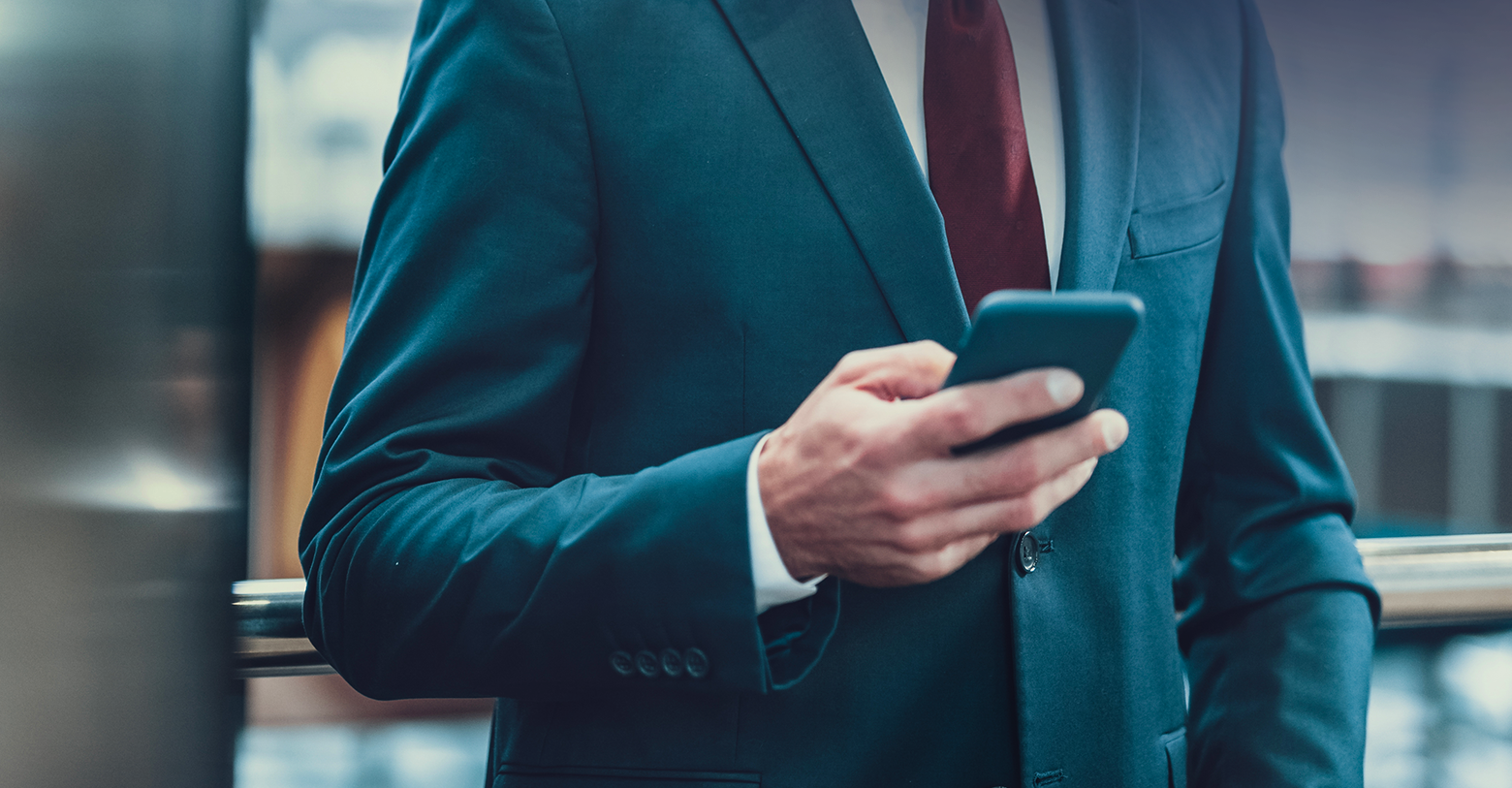 A man in a suit holding a mobile. 
