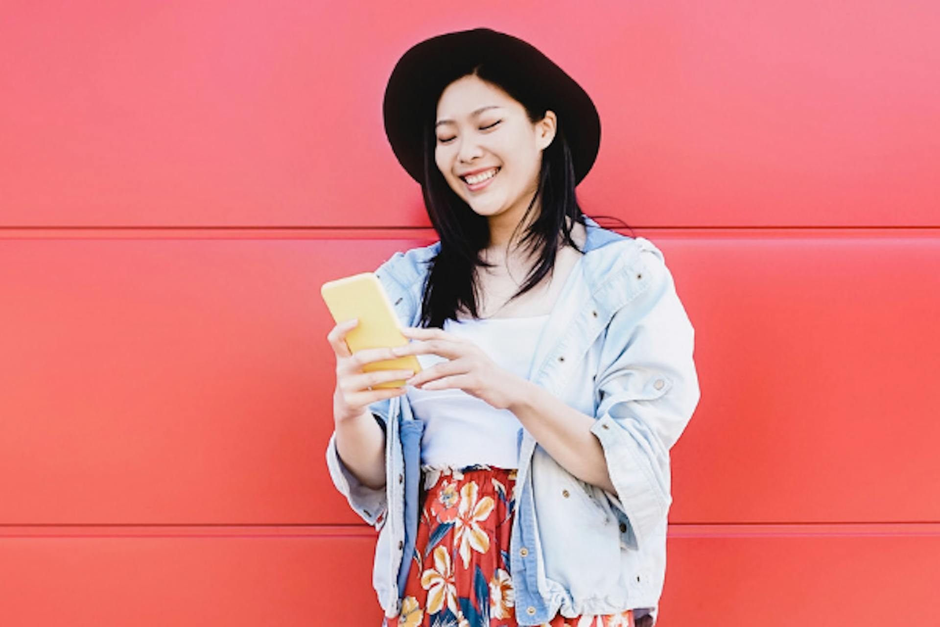 asian woman with smartphone influencer in front of red wall