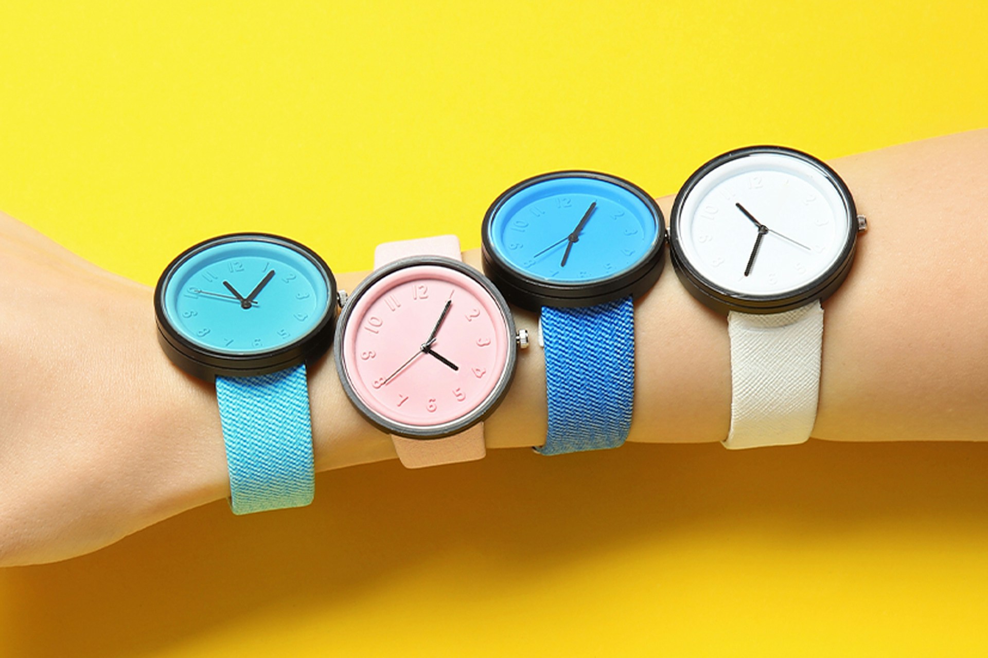 Person wearing multiple watches for different time zones on bright yellow background. Hero image for social media management blog post.