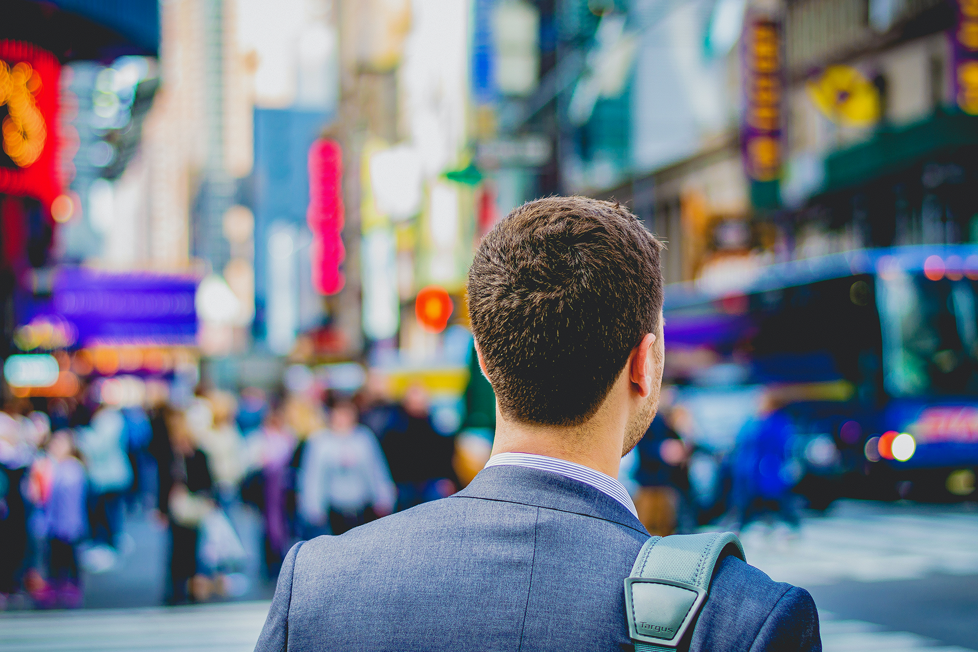 Man in a cityscape with a satchel and suit. 