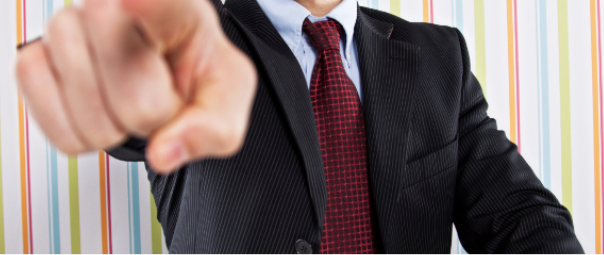 Picture of a man in a tie pointing at the camera accusingly