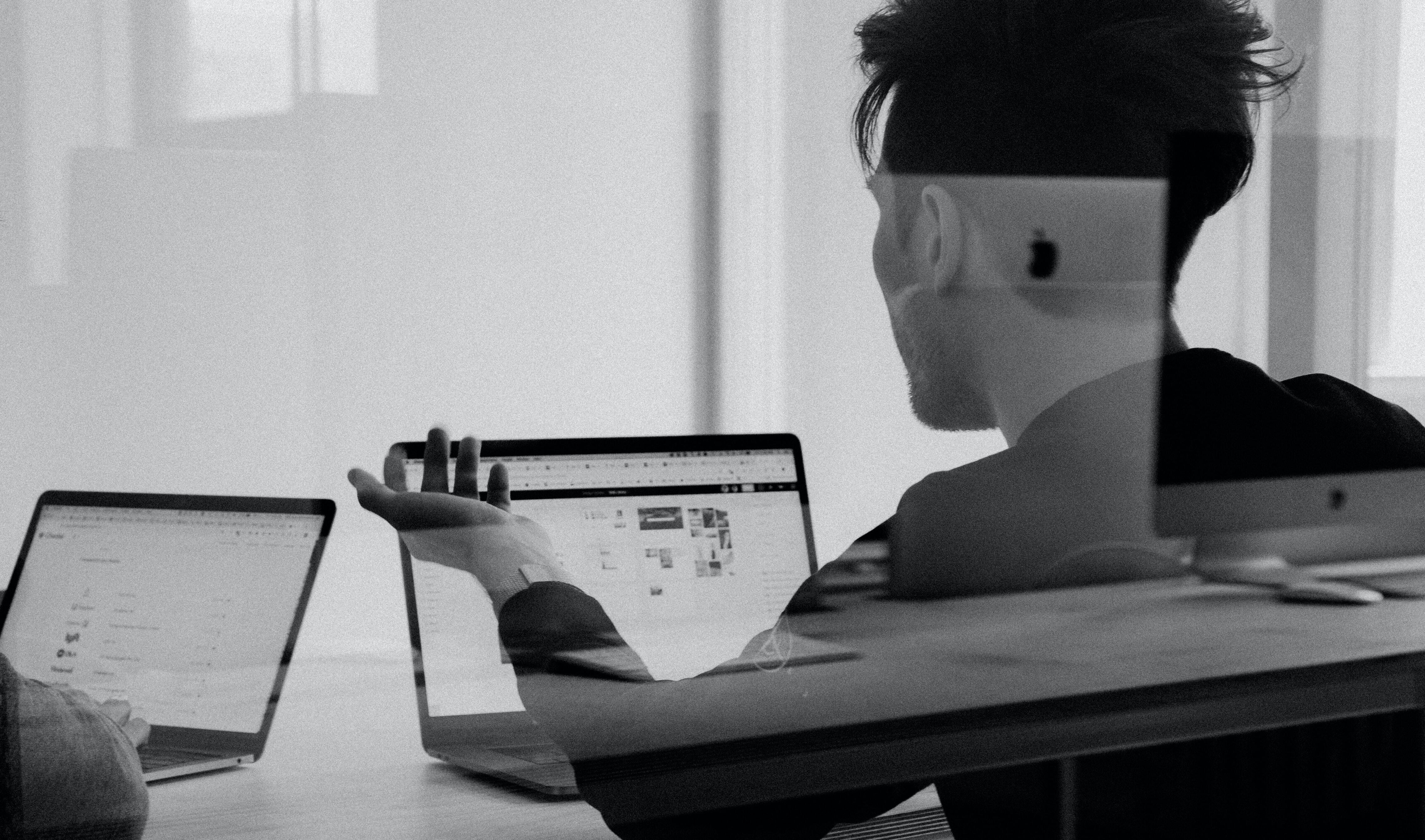 Black and white image of a man sitting at a desk with a laptop