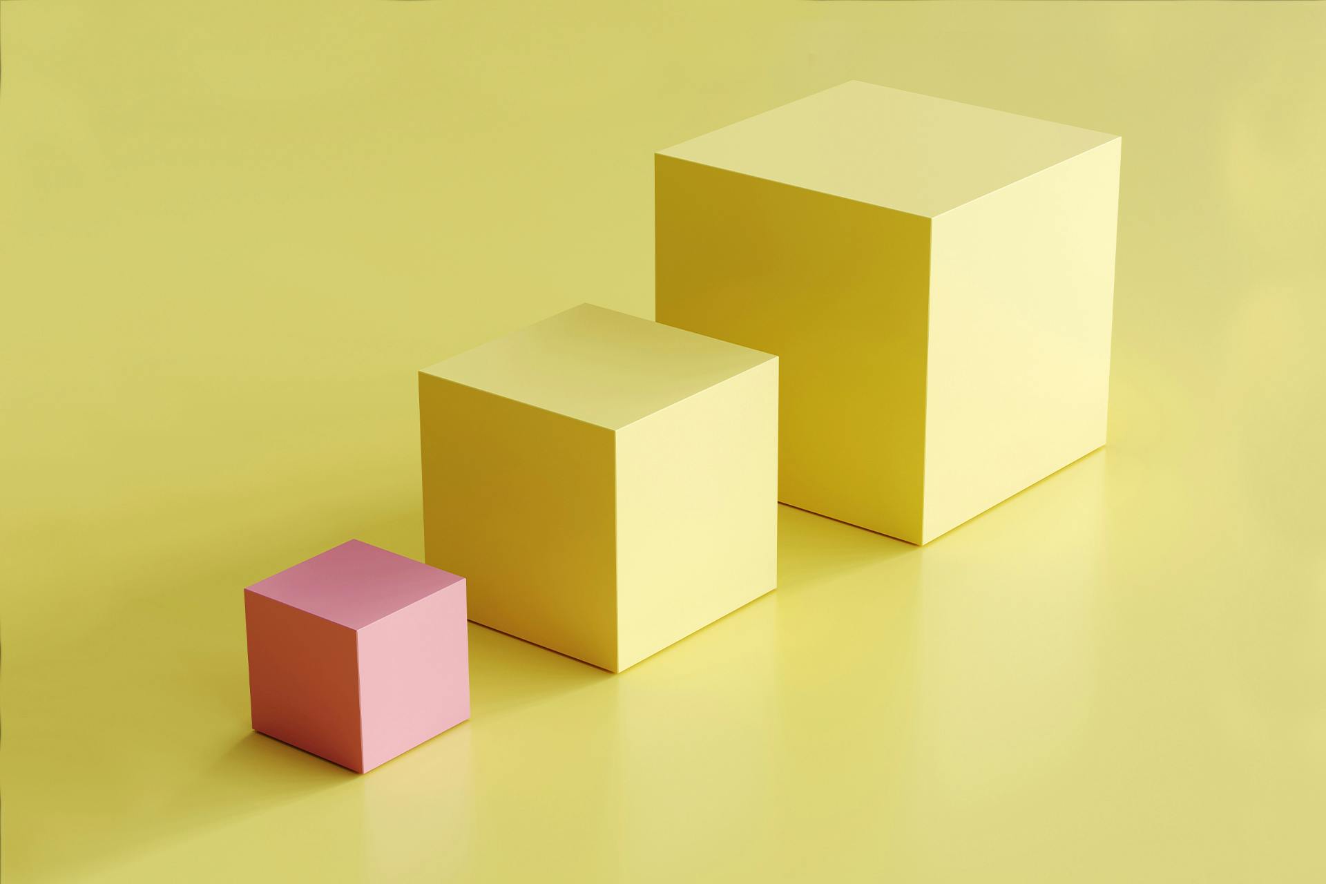 Een stel blokken: twee grote gele kubussen en een kleinere roze kubus. De roze kubus steekt duidelijk af tegen de andere gele kubussen, wat dit beeld perfect geschikt maakt voor onze blog over merkextensies en hoe je ze in je strategie kunt opnemen.