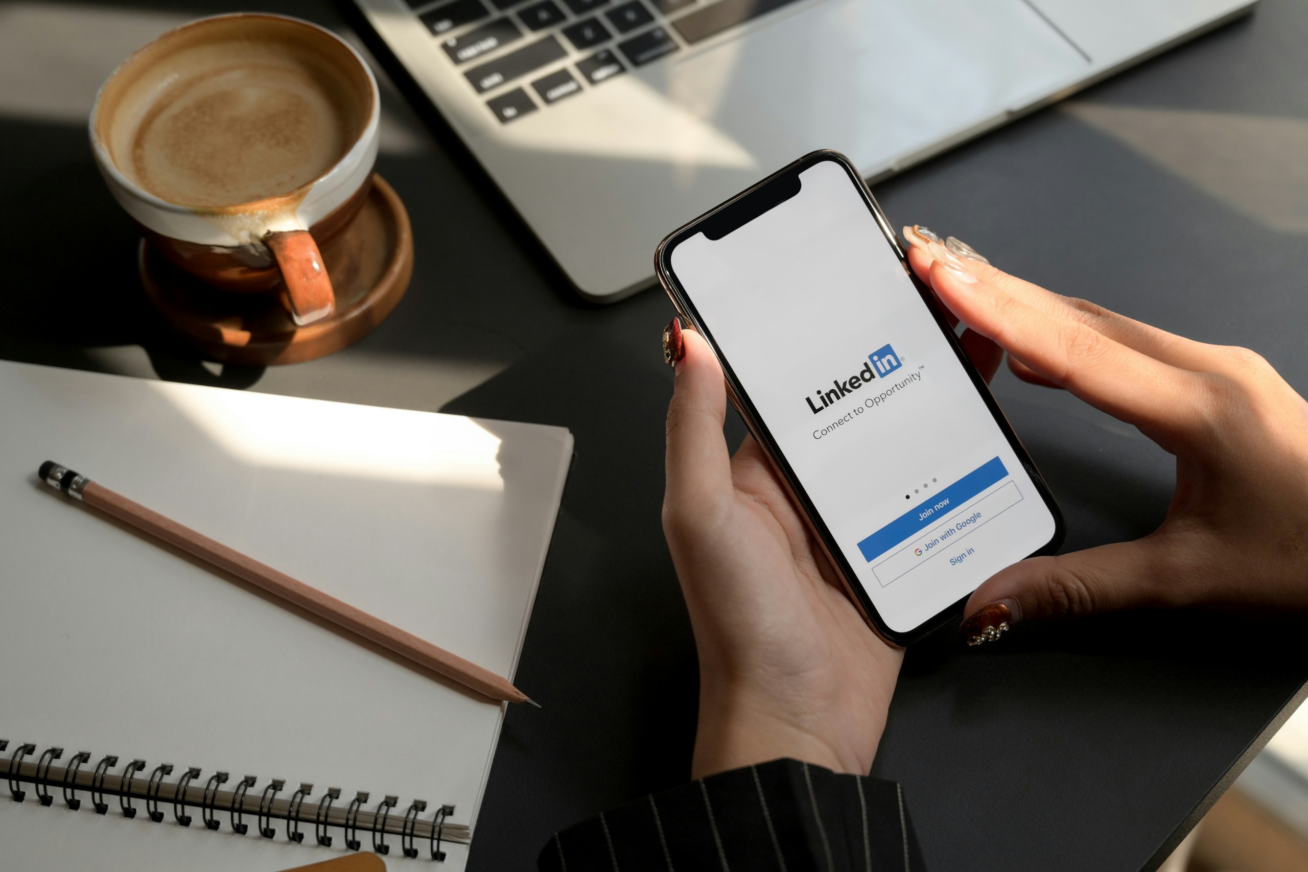 Personne qui tient un téléphone avec l'appli LinkedIn dans sa main