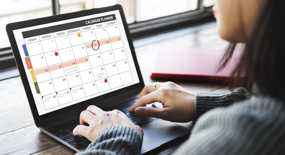 woman typing on a laptop with a social media content calendar on the screen