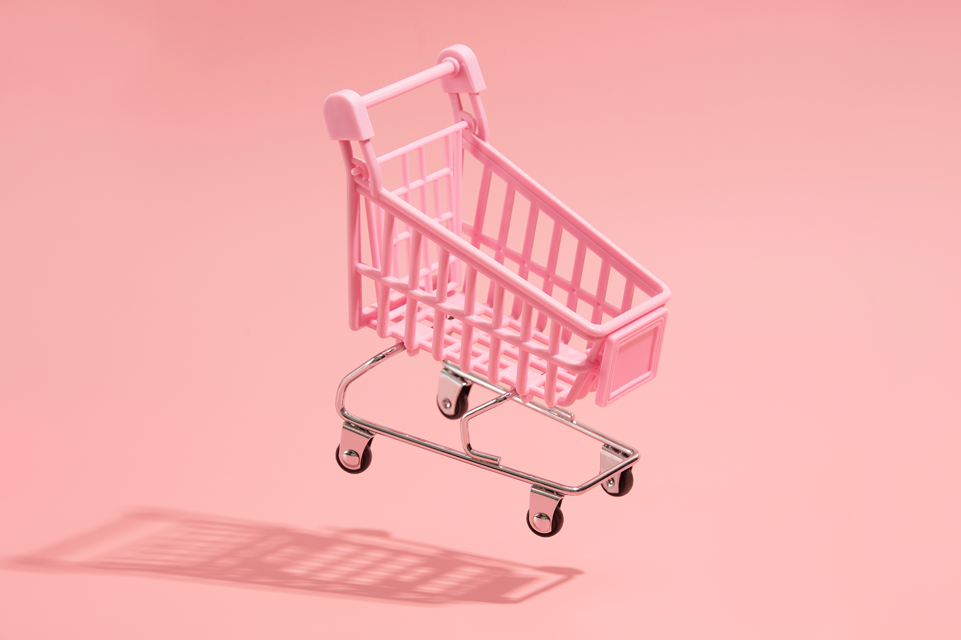 Pink miniature grocery cart on light pink background. Blog post on transactional marketing vs relationship marketing