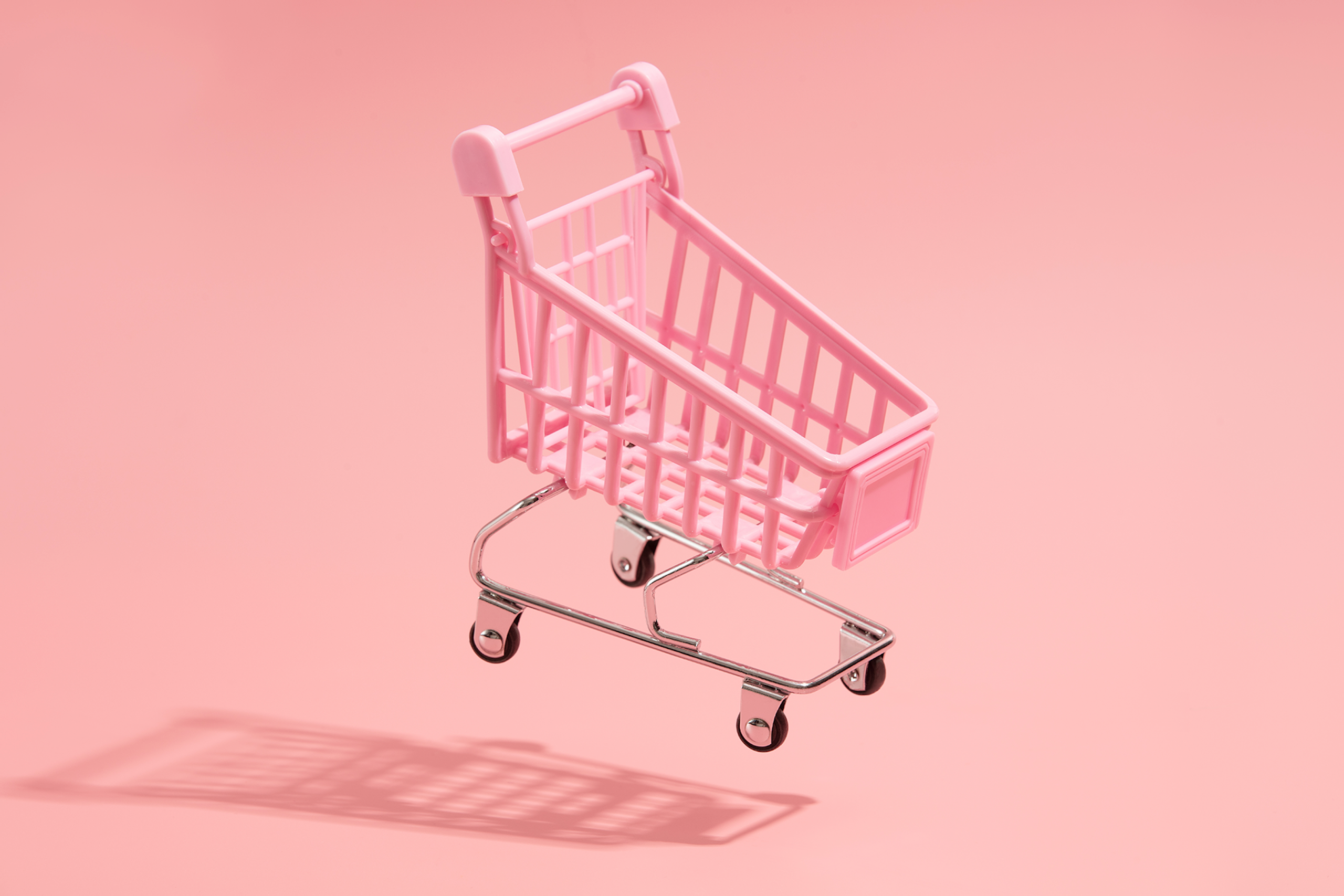 Rosa Miniatur-Einkaufswagen auf hellrosa Hintergrund. Blogbeitrag über Transaktionsmarketing vs. Beziehungsmarketing