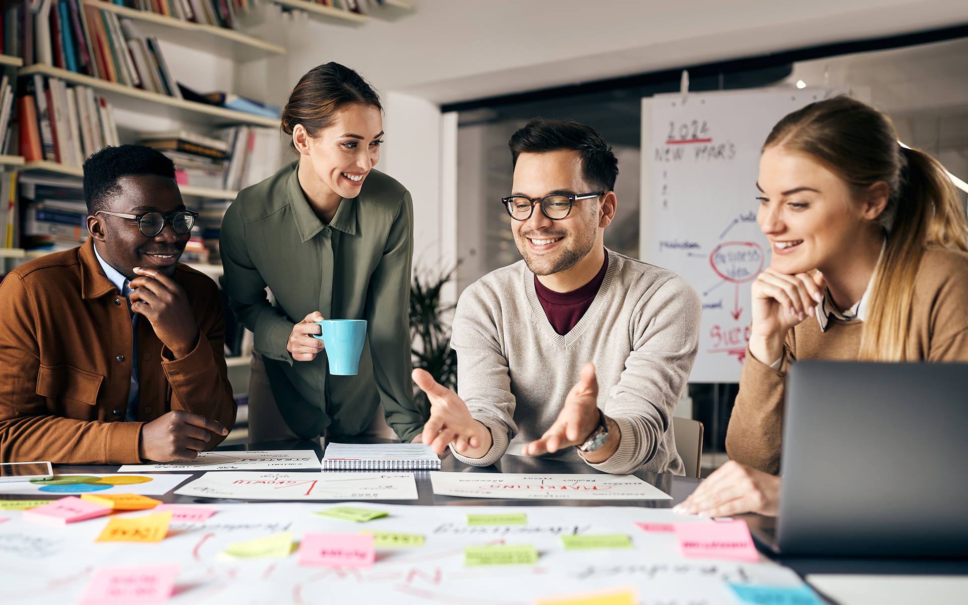 A diverse group of marketers smiling and planning out their campaigns. Marketing Trends for 2024 guide