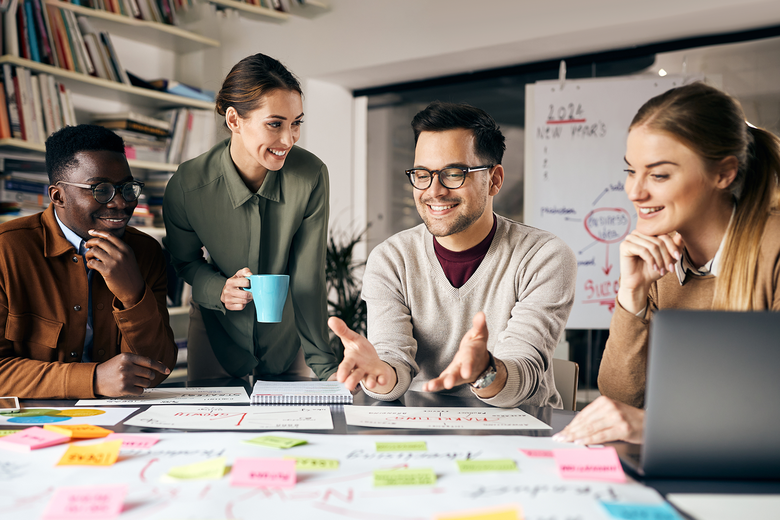 A diverse group of marketers smiling and planning out their campaigns. Marketing Trends for 2024 guide