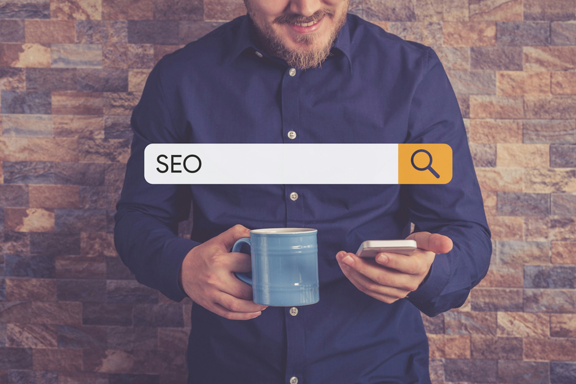 Man with a blue mug searching up SEO on his phone