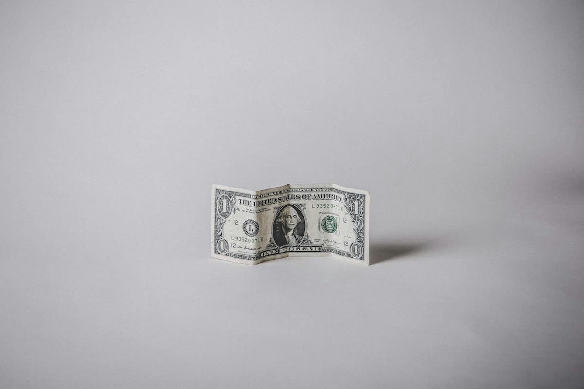 1 US dollar banknote against a white background for showcasing how much media monitoring costs