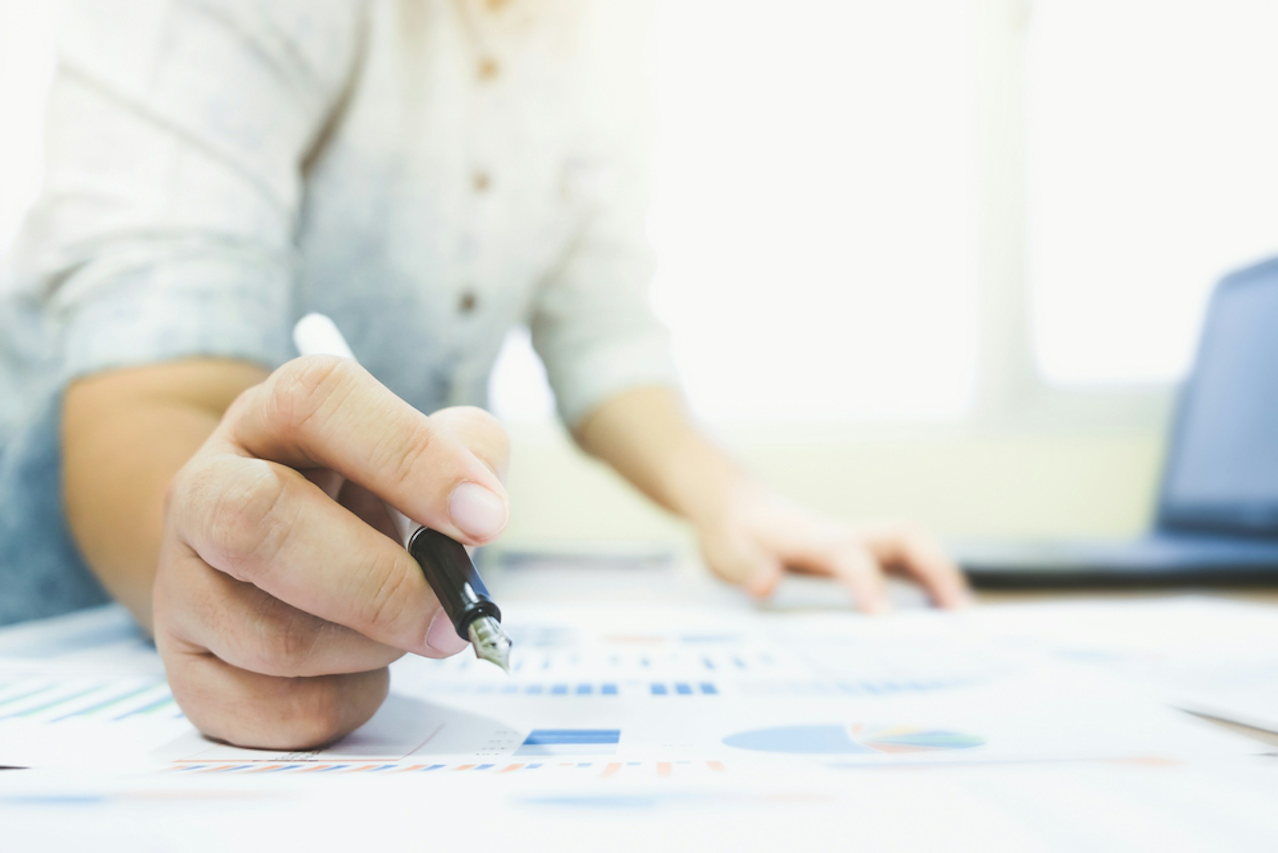 Man looking through charts on paper while using his laptop