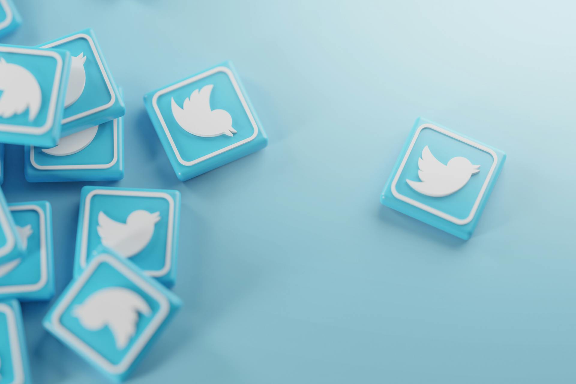 Twitterロゴの正方形のタイルが複数ブルーの背景に配置されている画像